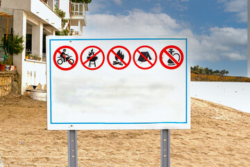 Large sign board with many illustrated symbols of restrictions in place on public beach in Edirne...