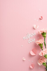 Mother's Day classy scheme. Overhead vertical view of affectionate greeting quote, little hearts, and paper confetti on a gentle rose background, offering space for text or advertisements