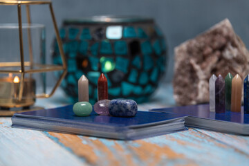 A tarot card reading setup with an array of colorful healing crystals on a weathered wooden table,...