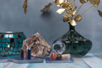 A serene tarot card reading space with assorted healing crystals, a candle lantern, and a geode on a weathered wooden surface.