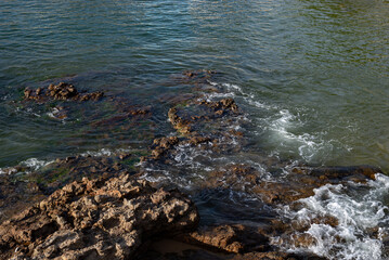 Dark sea rocks. Strong sunny day.