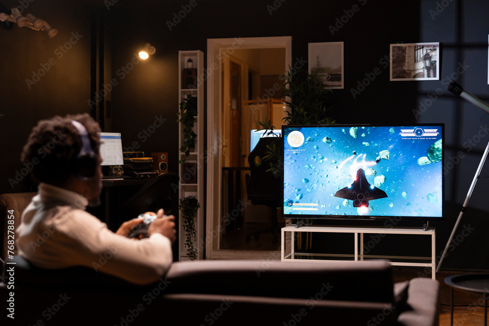 Poster bipoc gamer playing classic arcade action videogame, flying through space debris. man enjoying leisu