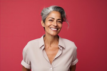 Smiling mature woman with grey hair looking at camera, isolated over red background
