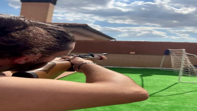 Video of a man practicing target shooting with a rifle in backyard