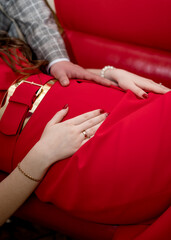 The hands of a man and woman on the belly of a pregnant woman	