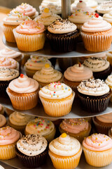 A tiered stack of cupcakes in an assortment of flavors