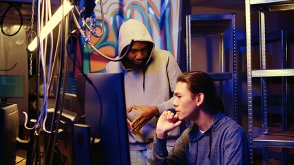 Hackers in underground hideout discussing ways to best hide their online activity through VPN and other methods after stealing data from victims, trying to avoid being detected by cybercrime police