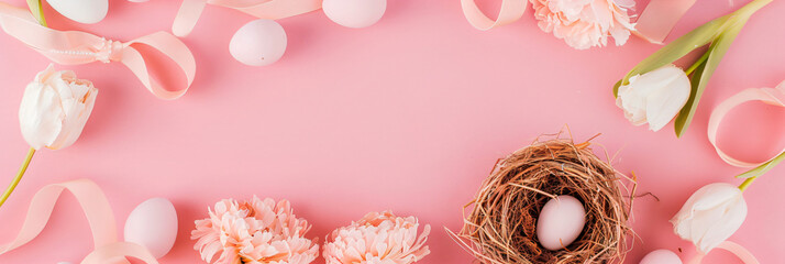 Frame with colored easter eggs and spring flowers on light pastel pink background. Happy Easter concept. Simple spring template, greeting card, banner. Top view, flat lay with copy space