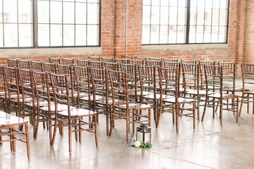 Wood chairs set up for an indoor wedding reception in a brick warehouse wedding venue - obrazy, fototapety, plakaty