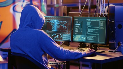 Hooded spy in underground hideout trying to steal valuable data by targeting governmental websites with weak security. Espionage specialist doing cyber attacks to gain access to sensitive info