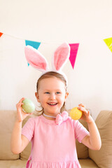 happy girl wearing bunny ears on Easter day play with Easter eggs at home