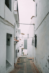 Fototapeta premium A narrow alley in a Spanish village with white walls and cobblestone street, embodying the quiet charm of rural Spain