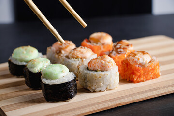 Set of sushi rolls on bamboo serving tray. Uramaki roll, chopsticks and soy sauce.