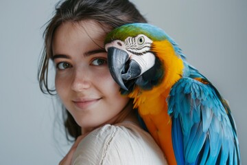 A young woman poses with a vibrant macaw on her shoulder, the connection between human and bird evident