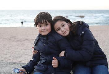 Hermanos abrazados en la playa al atardecer en invierno