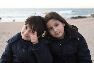 Fototapeta na wymiar Hermanos abrazados en la playa al atardecer en invierno