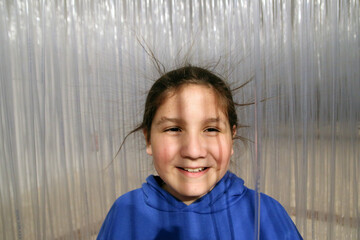 Niño con electricidad estática en el pelo rodeado de tubos plásticos de una exposición