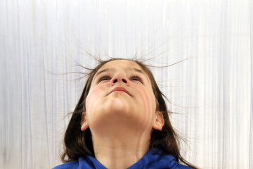 Niño con electricidad estática en el pelo rodeado de tubos plásticos de una exposición