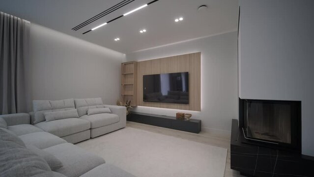 A serene living room transitions from dusk to illuminated comfort as ceiling lights brighten the space, highlighting the stylish sofa and fireplace