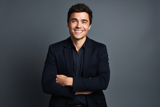 Portrait of a smiling young business man standing against grey background.