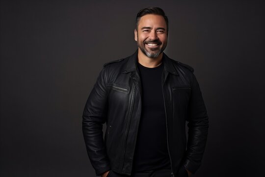 Portrait of a handsome man in a black leather jacket on a dark background.