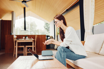 Smiling Woman using Laptop on Sofa in Home Office for Online Education and Communication...
