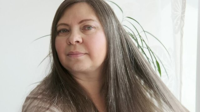 mature brunette woman examines long hair for signs aging, discovering gray hair, checkup, aging problems, concept female age, menopause, midlife crisis, hairloss problem, hormonal imbalance