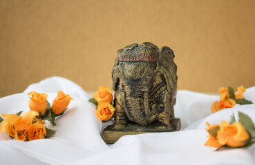 Antique Indian elephant statuette on white fabric and orange color flowers with copy space