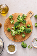 Raw broccoli florets on a cutting board, ready to roast with spices and olive oil