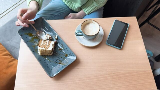 Anonymous woman enjoying casual coffee and cake break at a cafe table