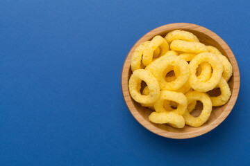 Corn ring crisps on color background, top view