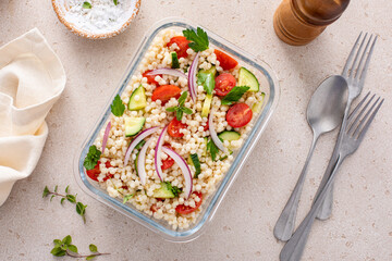 Pearl couscous salad with fresh vegetables and herbs in a meal prep container, healthy lunch or side dish