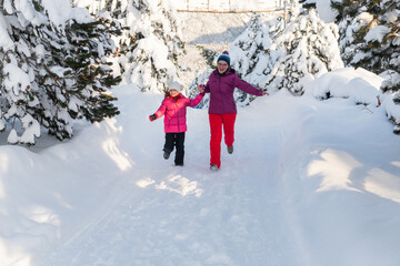 Fototapeta na wymiar A Mother and Daughter's Blissful Run Along a Snowy Winter Path