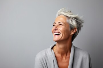 Portrait of a happy senior woman laughing against grey background with copy space