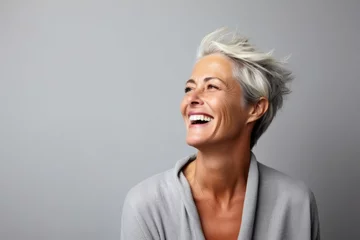 Fotobehang Portrait of a happy senior woman laughing against grey background with copy space © Chacmool