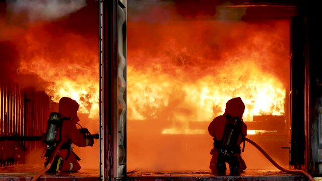 Firefighter fighting with fire flame protection property. Fireman wear hard hat, body safe suit uniform for protection from fire operation. Rescue trained in fire fighting extinguisher hazardous fires