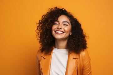 Cheerful african american woman in leather jacket on orange background