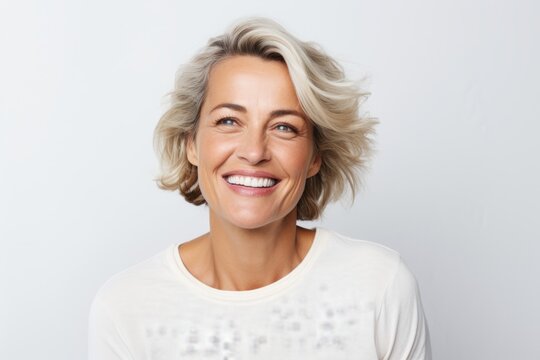 Portrait of happy smiling mature woman with blond hair over grey background