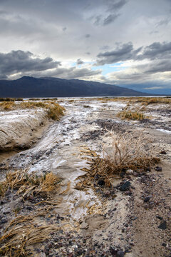 Death Valley riverbed with distant mountains uder a dramatic sky