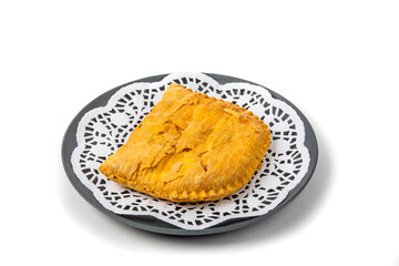 A West Indies meat patty on a black plate isolated on white