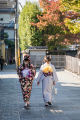 two women walking down a street, one of which has flowers on her head.