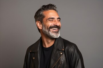Handsome middle aged man with beard and mustache in black leather jacket on grey background