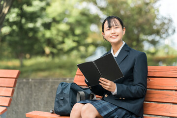 公園のベンチで勉強する制服姿の女子中学生・女子高生
