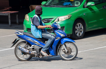 Fototapeta na wymiar The mototaxi driver in a blue vest ride on the street, Thailand