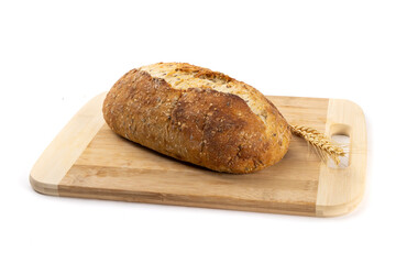 A whole loaf of artisanal crusty bread on a wooden cutting board isolated on white