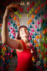 Funny, cute, self-confident adult girl posing in a red dress and taking a selfie. A middle-aged model at a photo shoot in a studio for social networks. Leisure activities