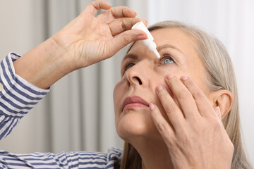 Woman applying medical eye drops at home