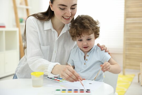 Mother and her little son painting with watercolor at home, closeup