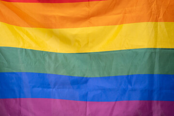 The gay pride rainbow flag waving against clean blue sky, close up