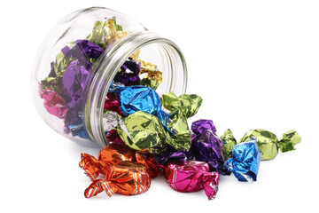 Glass jar with candies in colorful wrappers isolated on white